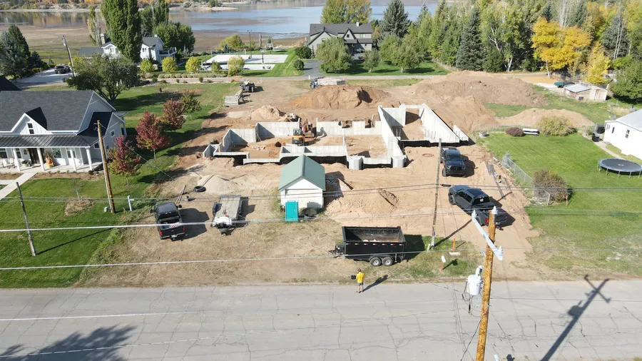 Aerial view of poured foundation walls for a custom home in Huntsville, Utah, with Pineview Reservoir behind