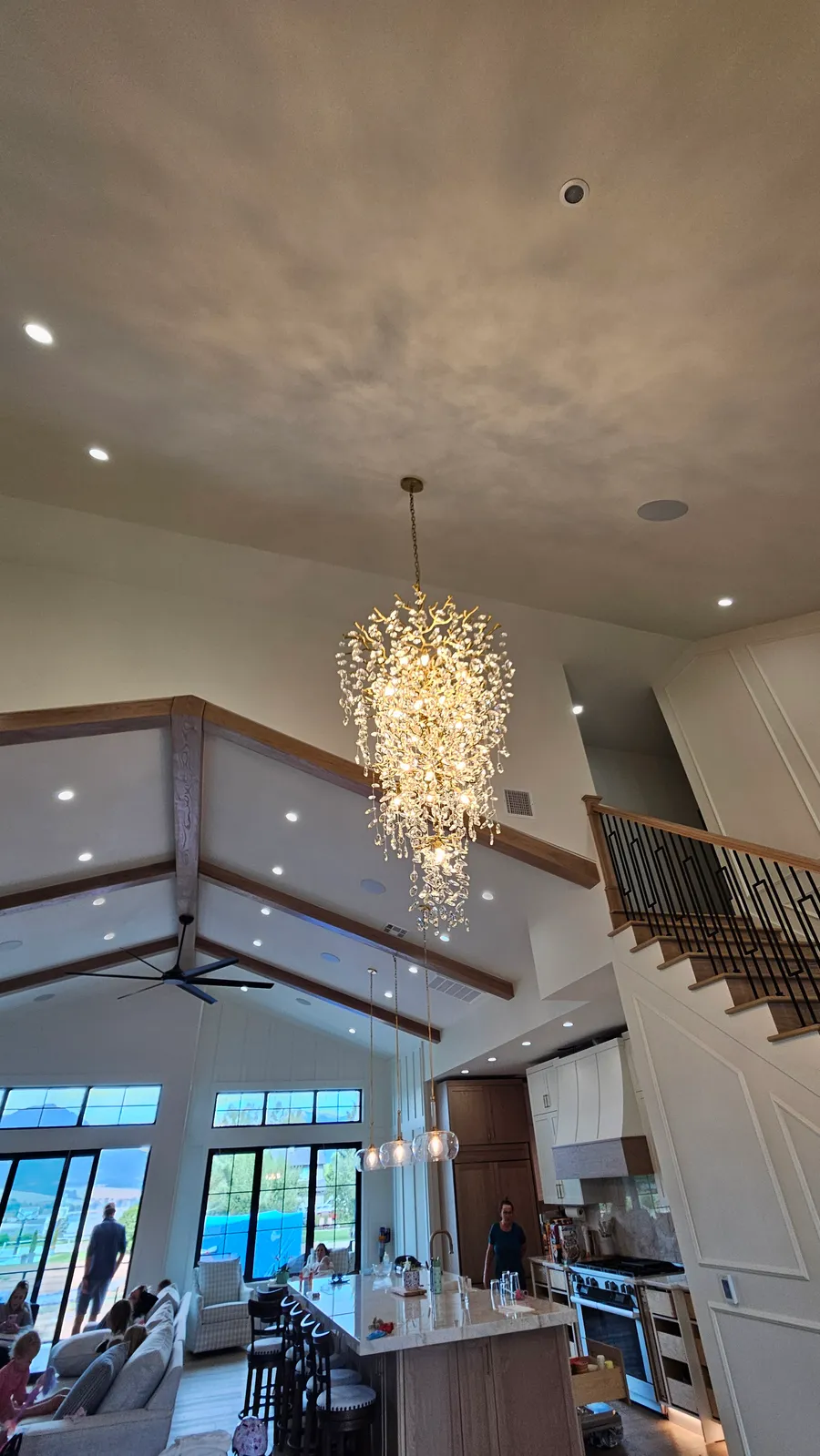 Completed vaulted great room with wood beams, crystal chandelier, and floor-to-ceiling windows in the Huntsville custom home